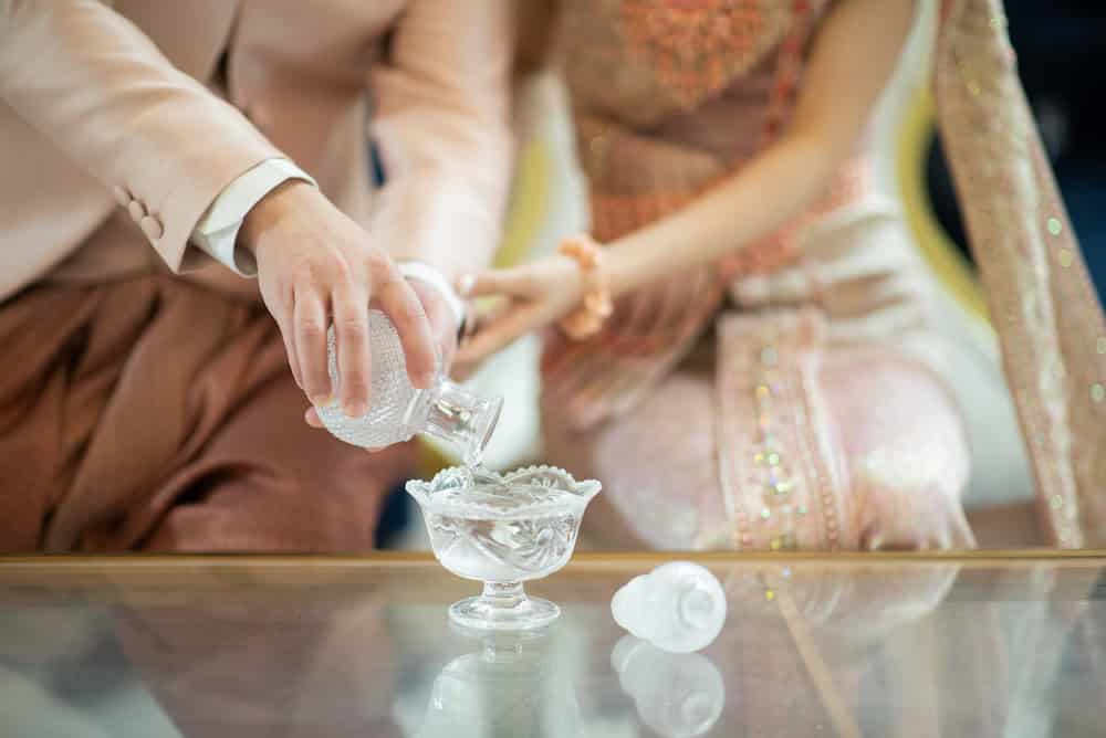 A couple performs the water pouring tradition as part of a Thai wedding ceremony