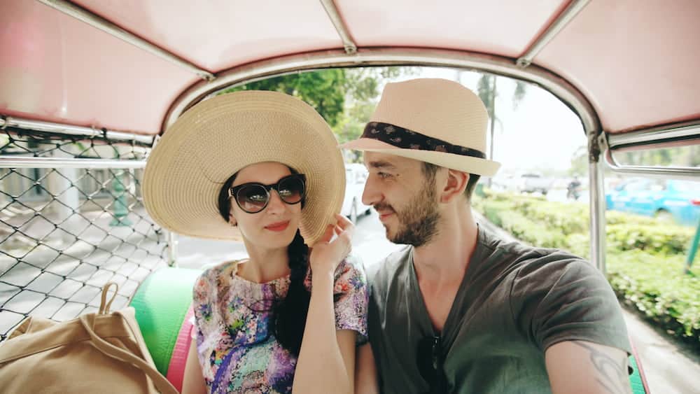 A couple poses for a selfie in a Bangkok tuk-tuk
