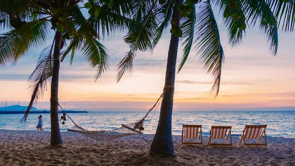 A hammock and beach chairs facing the sunset on Na Jomtien beach