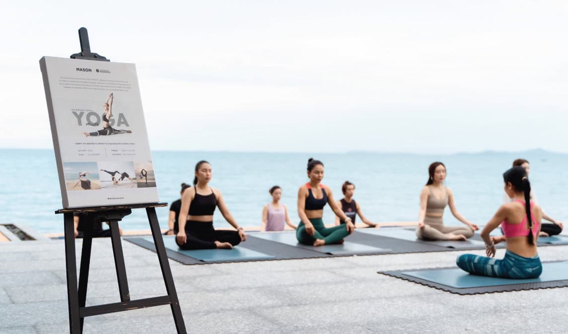 a woman doing yoga on the beach holds a pose as morning light fills the sky